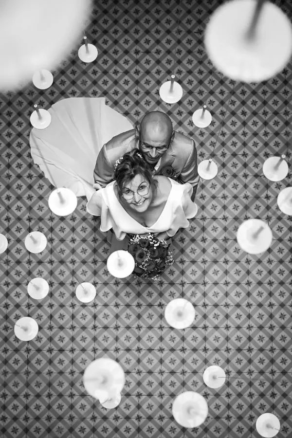 Prise de vue aérienne artistique d’un couple de mariés et lumières suspendues, par AEL Photos