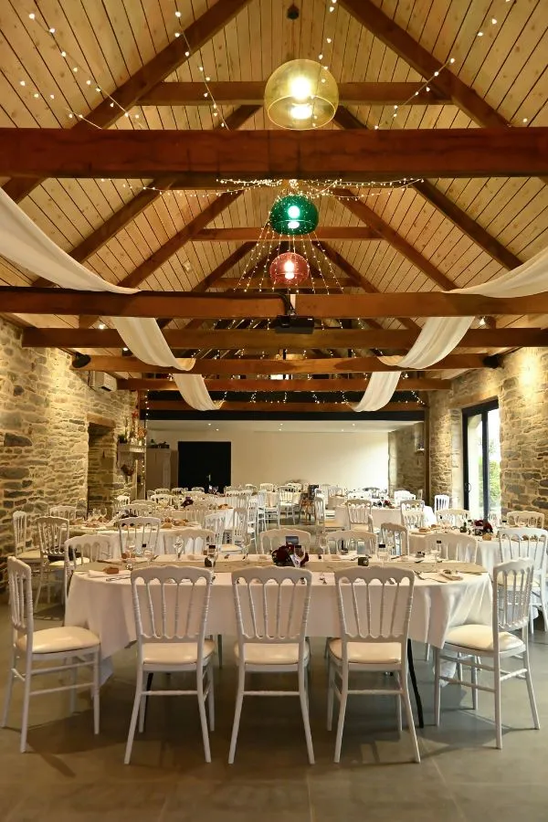 Vue intérieure d'une salle de réception en pierre décorée avec goût pour un mariage chaleureux, mariage photographié en Bretagne par Ael Photos