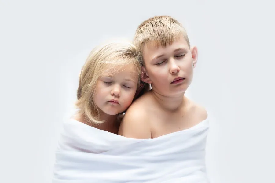 Portrait studio d'enfants frère et soeur blottis l'un contre l'autre et enveloppés dans un drap, par Ael Photos dans son studio à Pont de Buis, Finistère