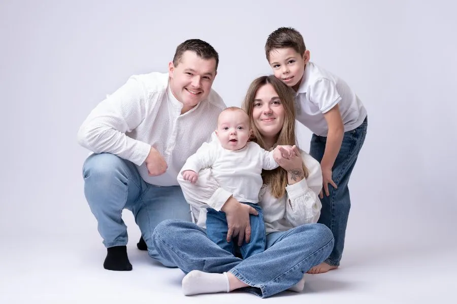 Portrait de famille assise au sol en studio, parents et enfants réunis