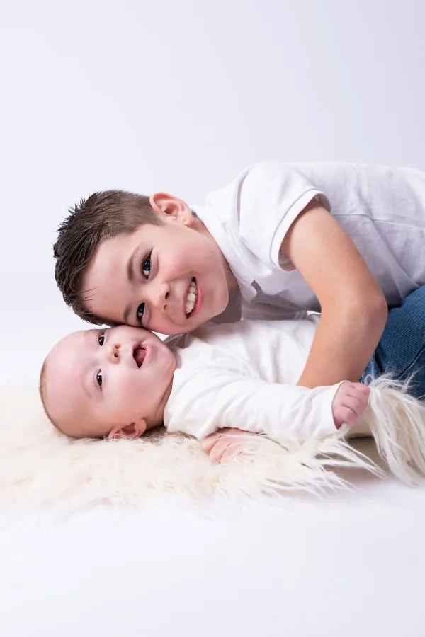 Portrait de fratrie en studio, grand frère allongé près de son bébé