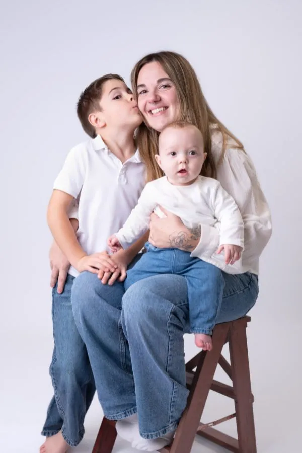 Portrait en studio d’une maman assise sur un tabouret avec ses deux enfants, ambiance douce et naturelle