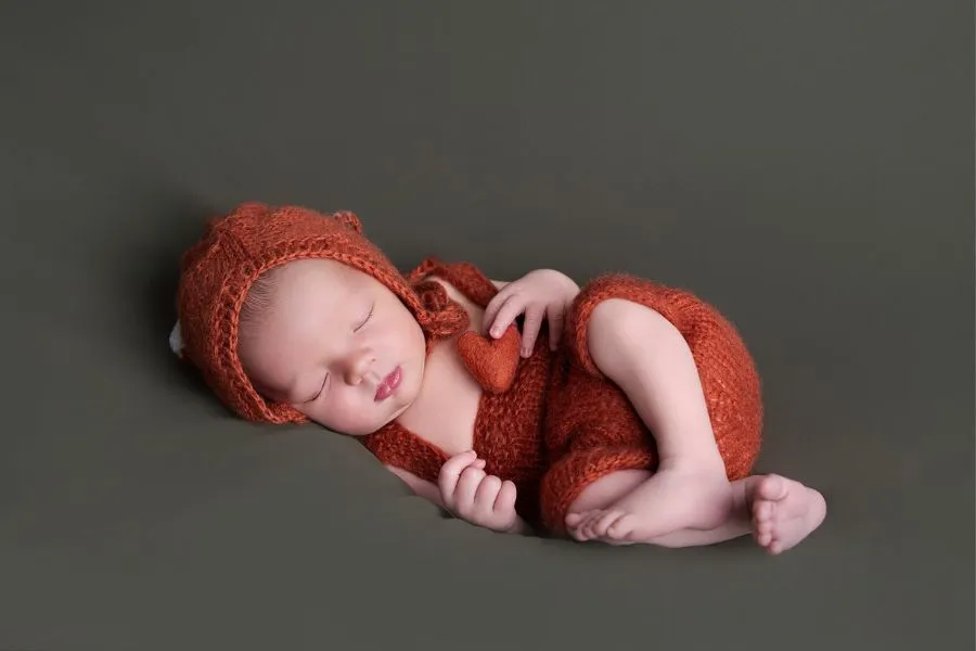 Bébé nouveau-né endormi en tenue tricot orange photographié par AEL Photos au Faou
