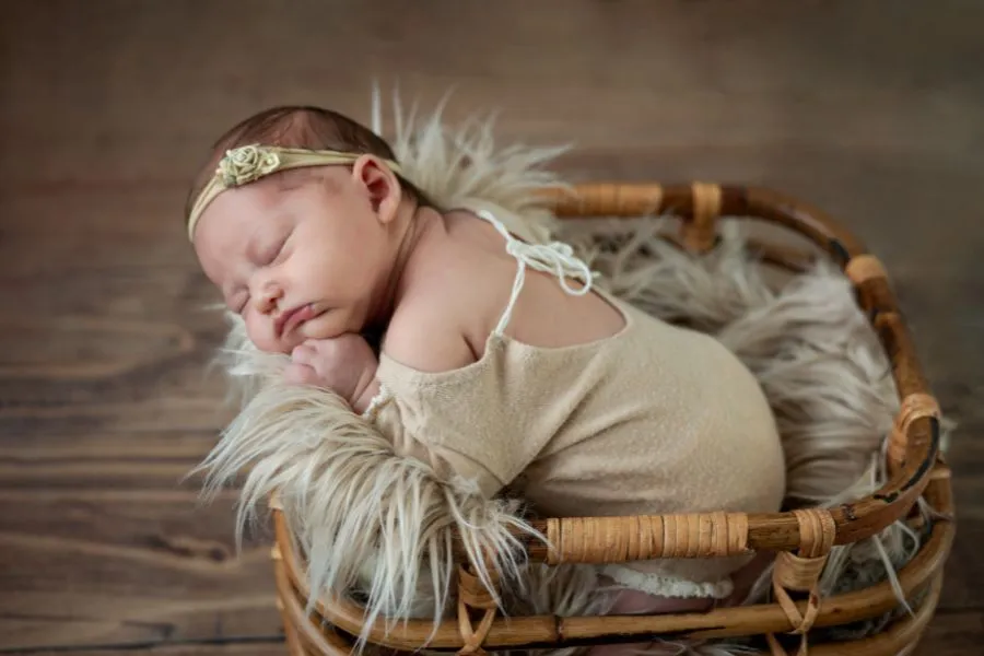Bébé nouveau-né endormi dans un panier en bois lors d’une séance photo au Faou