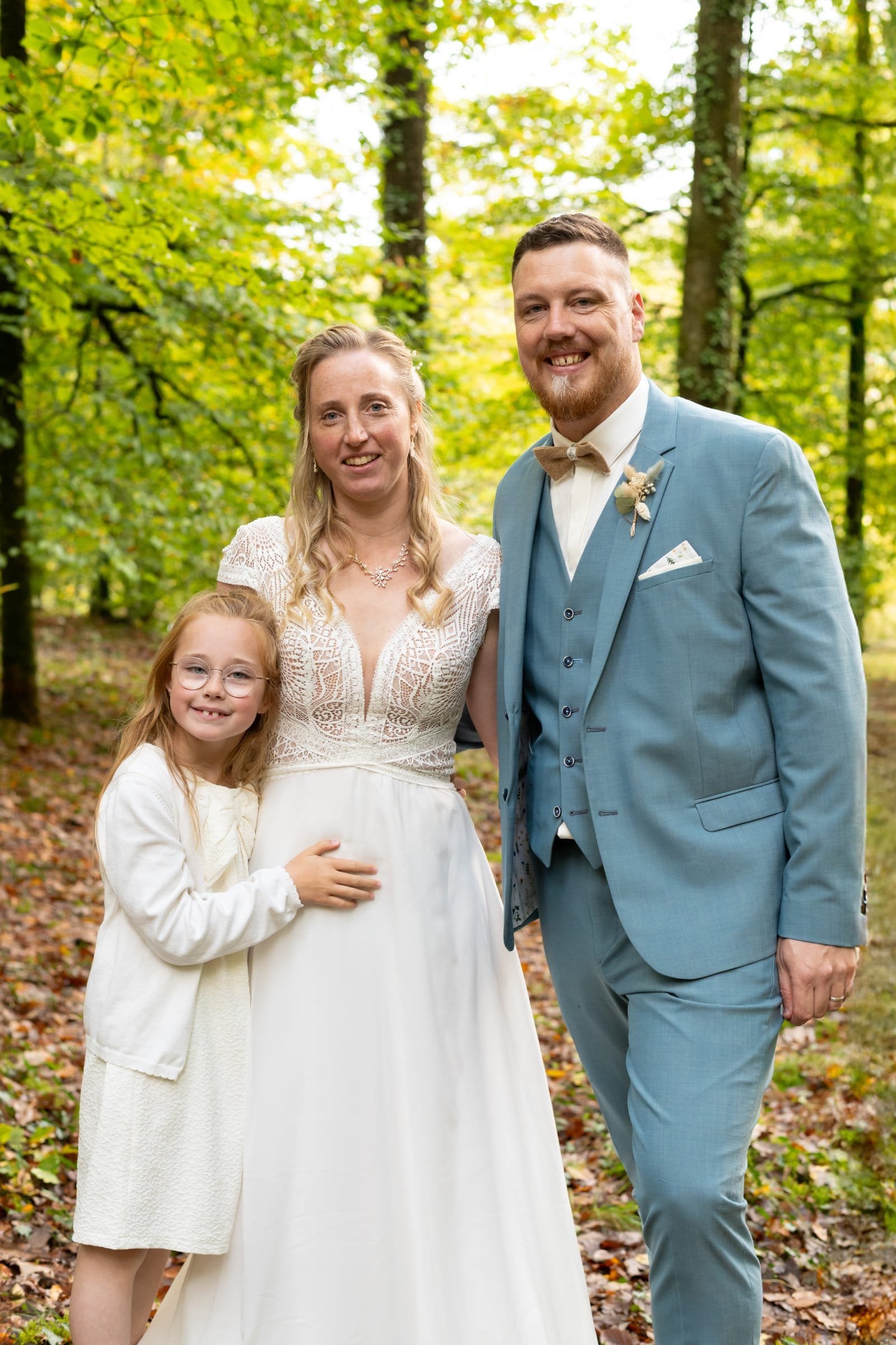 Portrait de mariage du couple marié avec une fillette avec en fond une forêt, par AEL Photos, Finistère