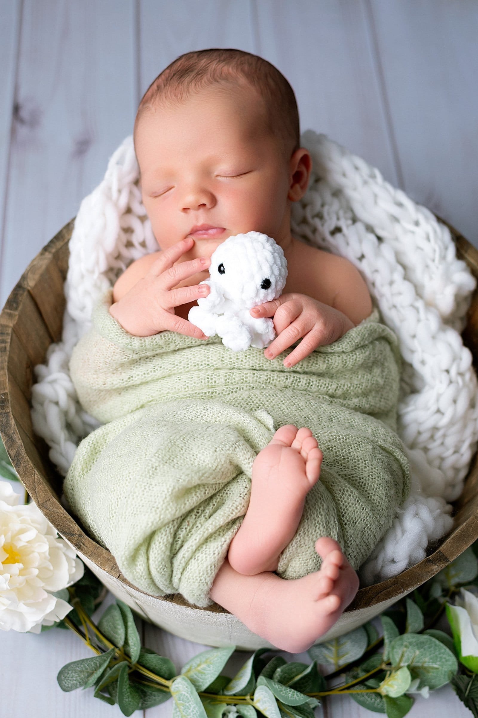 Séance photo nouveau-né en studio au Faou, bébé endormi dans un panier avec doudou blanc