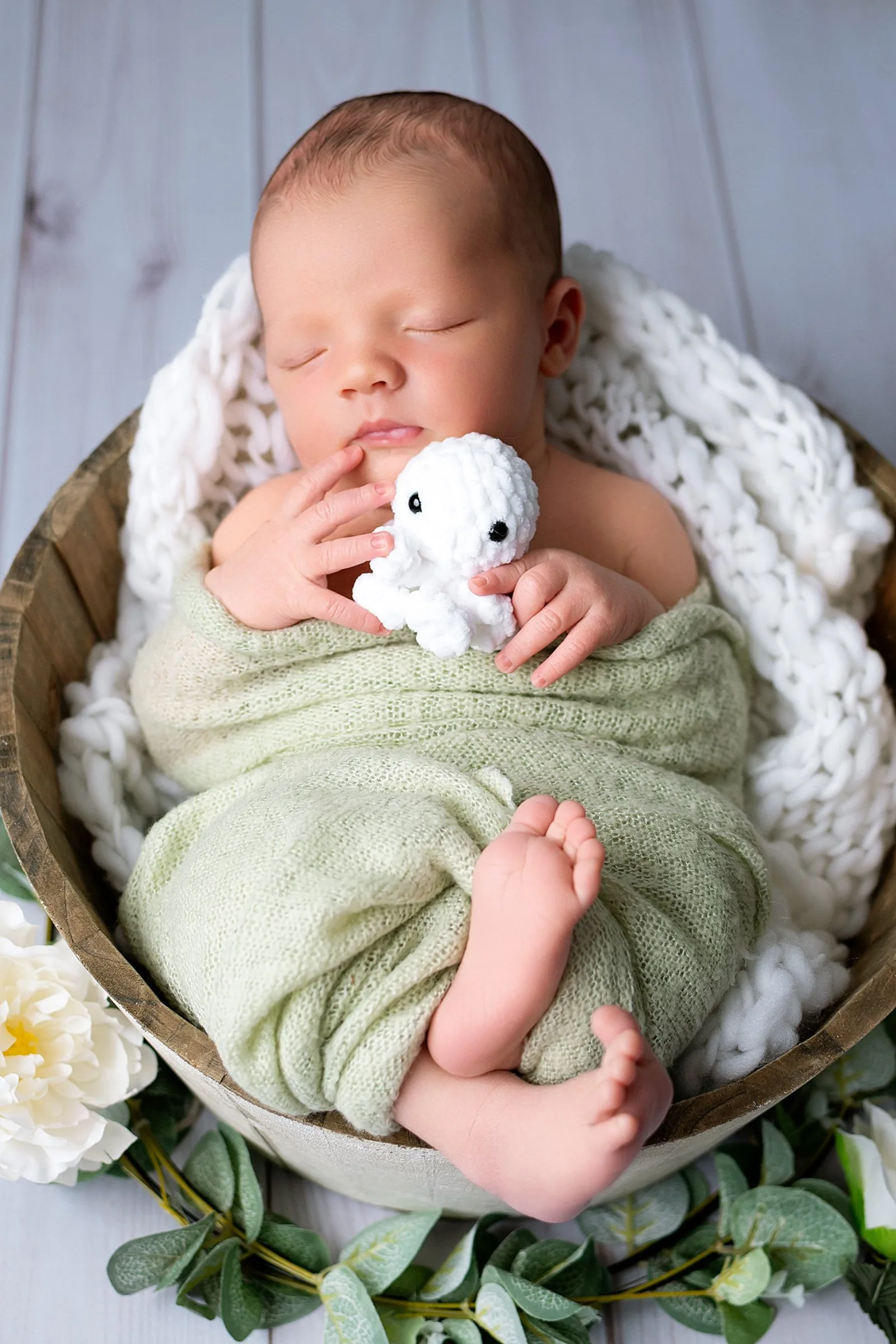 Séance photo nouveau-né en studio au Faou, bébé endormi dans un panier avec doudou blanc