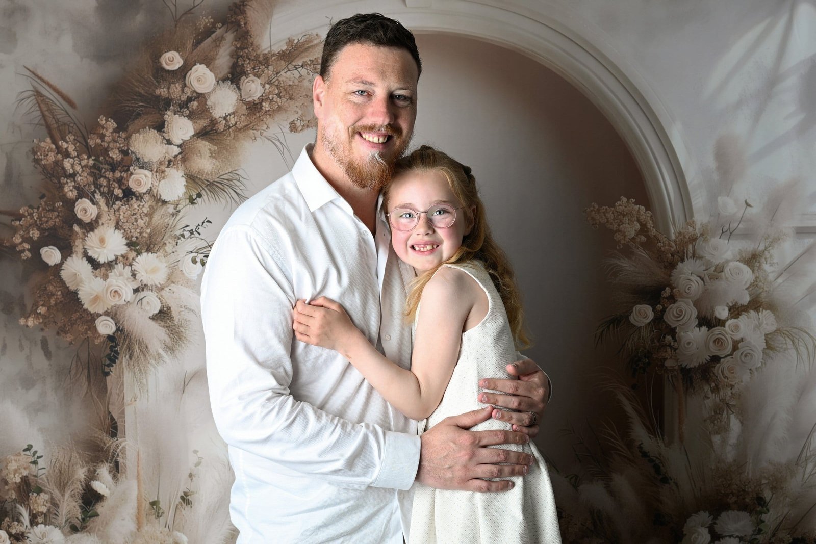 Portrait de famille d'un père qui tient sa fillette dans ses bras, au studio AEL Photos au Faou